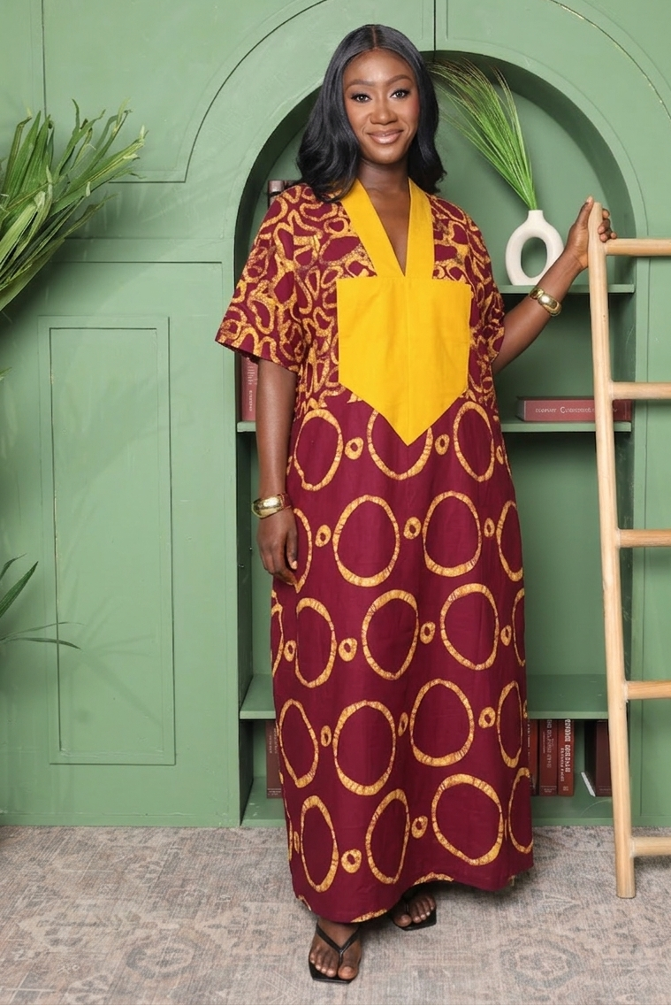 Woman in a patterned dress standing in front of a green wall with a wooden ladder.